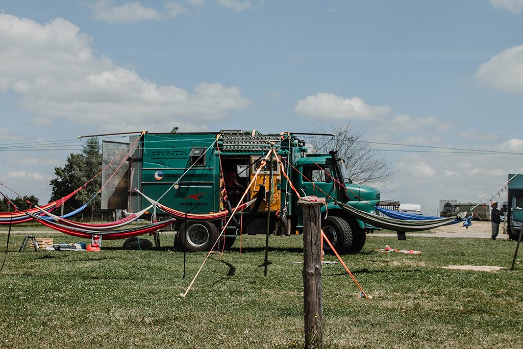 grüner Oldtimer LKW als Camper mit Hängematten davor