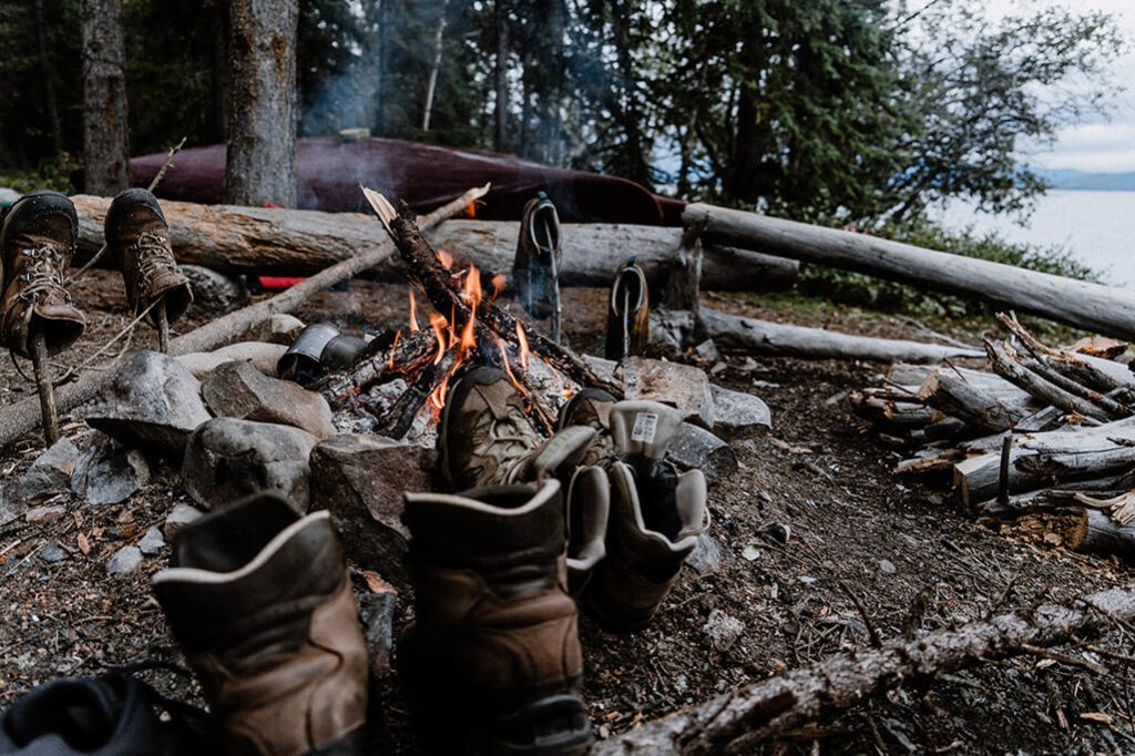 Brennendes Lagerfeuer mit trocknenden Wanderschuhen drumherum.