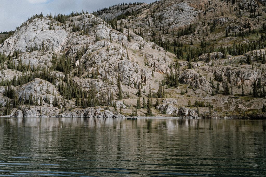 Kanu auf dem Lake Laberge im Yukon, felsiges Ufer im Hintergrund