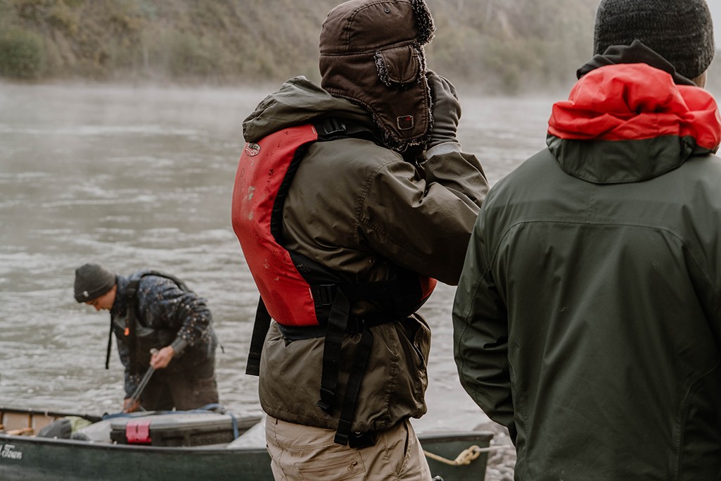 Warm angezogene Person wärmt sich Hände und steht am Yukon Fluss.