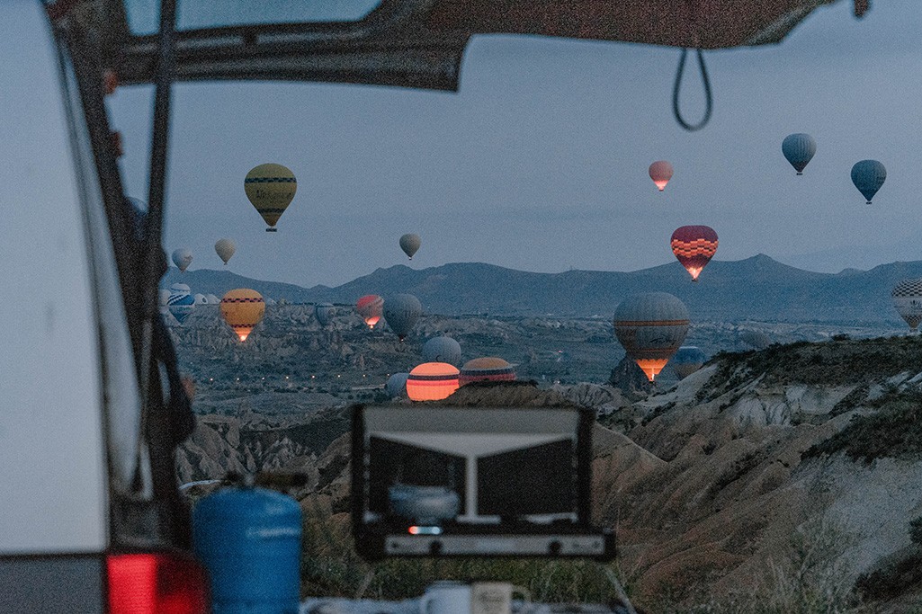 Kocher auf selbstgebautem Heckauszug Küche, Heißluftballons im Hintergrund. 