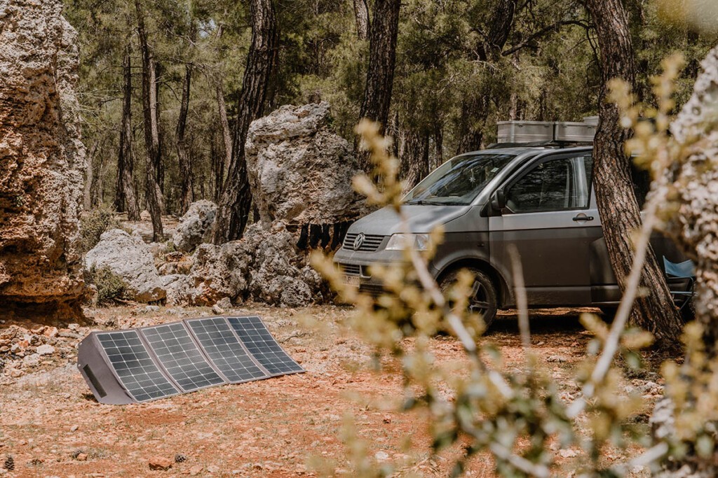 Solartasche steht ausgeklappt vor VW T5 Camper im Gelände.