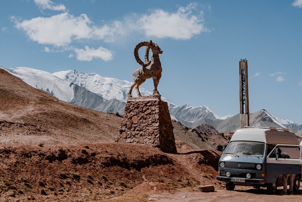 VW T3 Camper am Kyzyl-Art-Pass, daneben steht ein Steinbock als Statue.