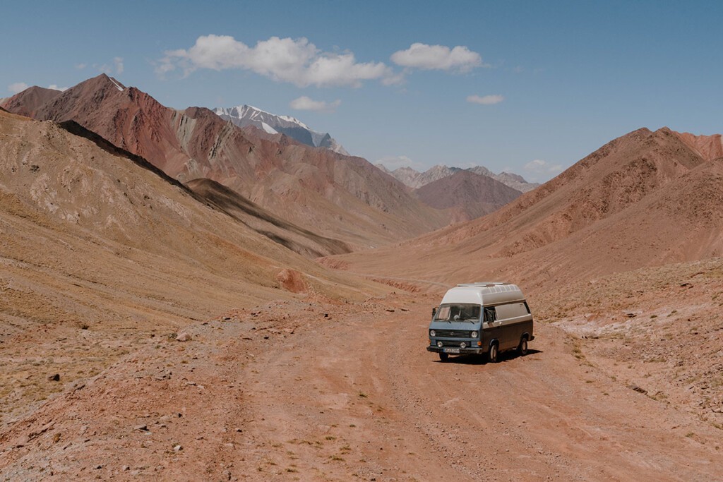 VW T3 Camper steht auf Schotterpiste zum Kyzyl-Art-Pass, daneben ragen Berge in die Höhe.