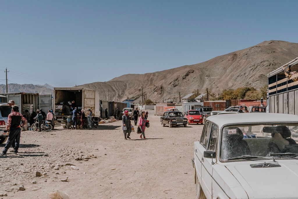 Blick über den Container-Markt in Murghab. Rechzs und links stehen Container, Menschen laufen über den staubigen Weg dazwischen.