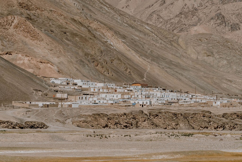 Blick auf einige Häuser von Murghab, die sich an die Ausläufer von einem Berghang schmiegen.