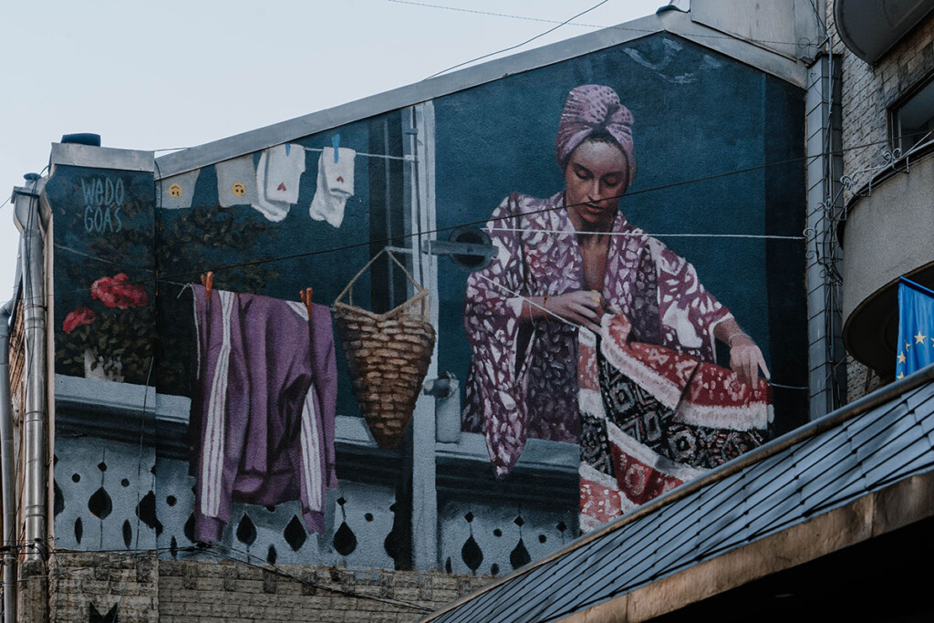 Street-Art in Tbilisi: Frau hängt Wäsche auf eine Leine.