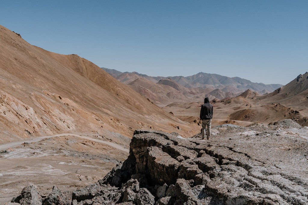 Person steht am Ak-Baital-Pass in Tadschikistan und blickt über karges Tal und braune Berge.