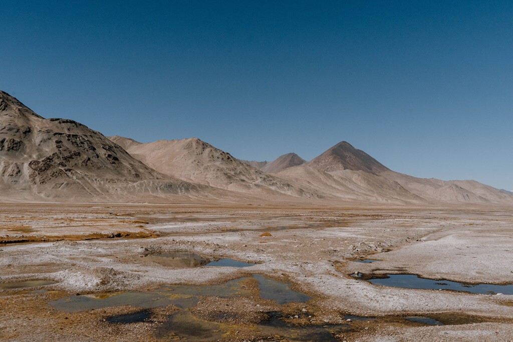 Seichtes, fast ausgetrocknetes Flussbett im Pamir-Gebirge mit kargen Bergen im Hintergrund.