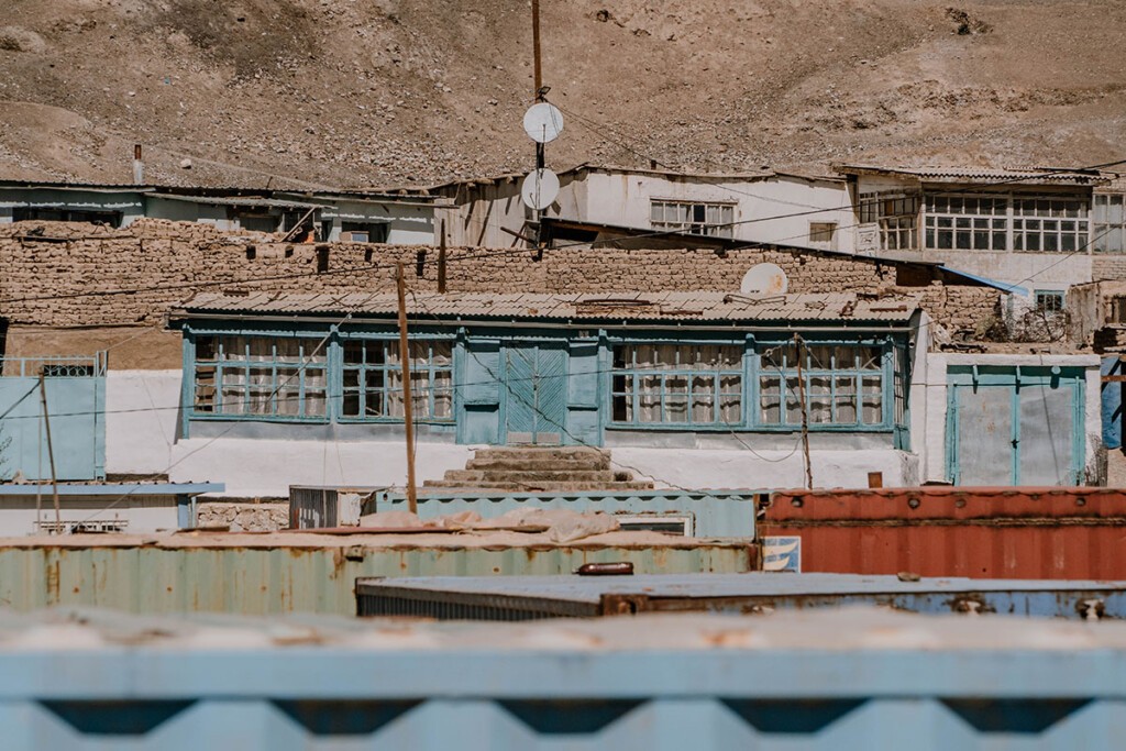 Weißes Haus mit blauen Fenstern, wettergegerbt, oberhalb vom Container-Markt in Murghab in Tadschikistan.