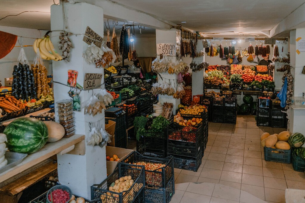 Kleiner Obst- und Gemüsemarkt in Mestia. Lebensmittel liegen in Kisten oder hängen an Wänden.