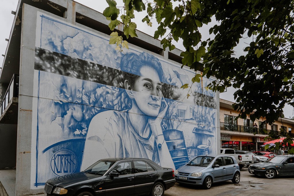 Die Suche nach schöner Street-Art zählt zu meinen Georgien Reisetipps. Auf diesem Foto ist eine Frau in Blau-Weiß an eine Hauswand in Ozurgeti gemalt.