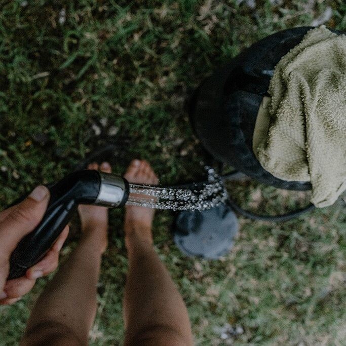 Person nutzt Campingdusche zum Pumpen