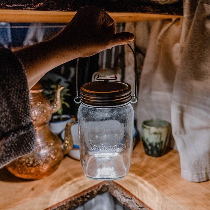 Person hält Sonnenglas im Camper, Solarlampe als Camping Geschenk