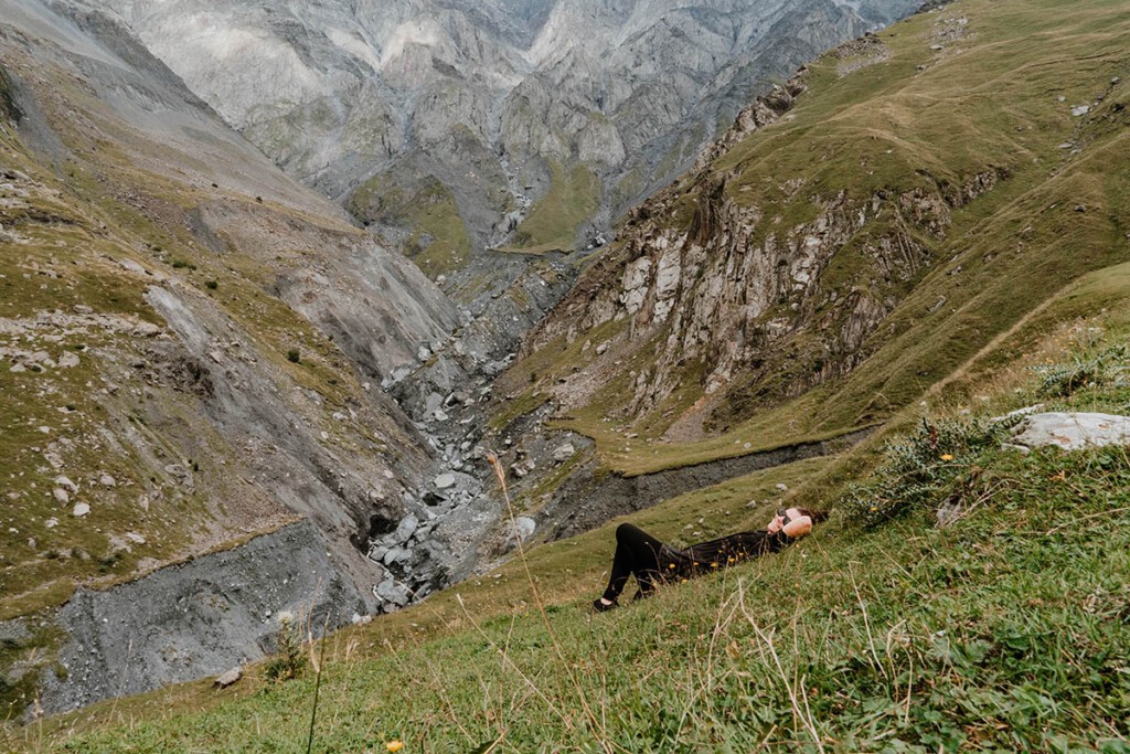 Elisa Model vom Camping Blog take an adVANture liegt auf Wiese im Kaukasus und blickt in die Kamera.
