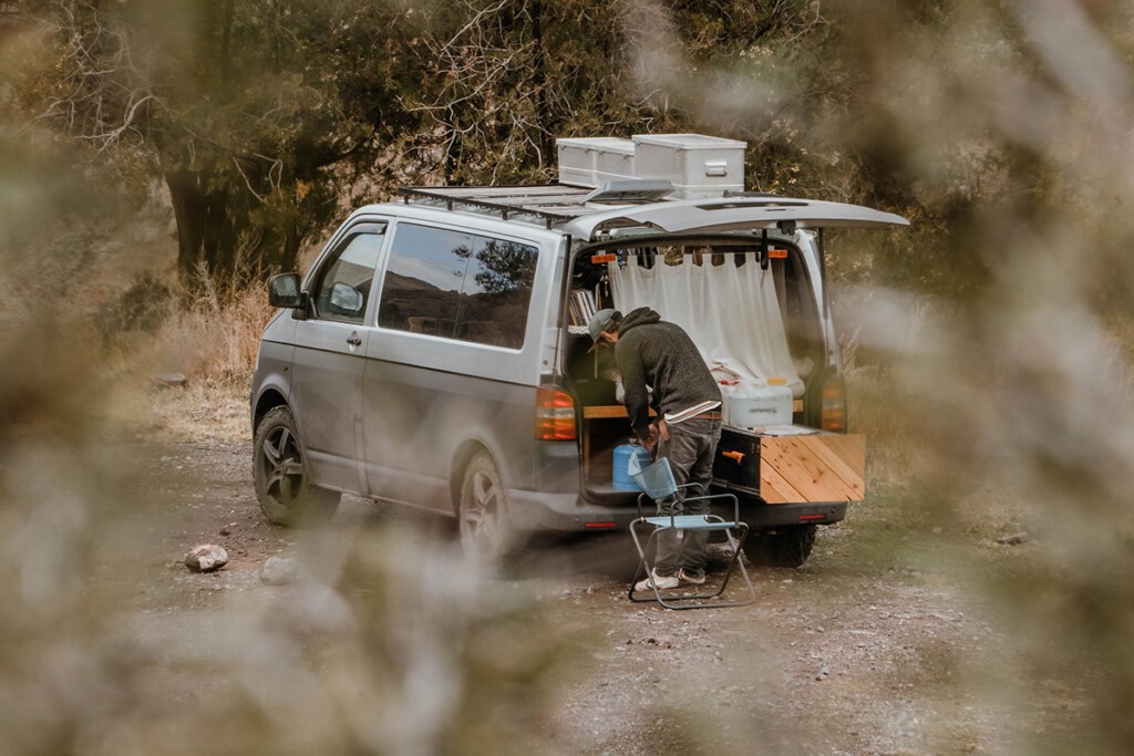 Silber-grauer VW T5 Camper mit geöffneter Heckklappe und ausgezogener Heckschublade.