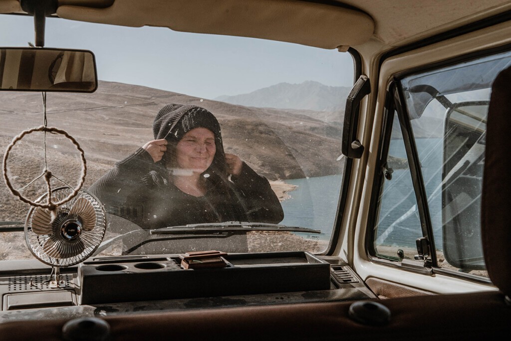 Elisa Model vom Camping Blog take an adVANture steht vor ihrem VW T3 Camper und blickt durch die Scheibe in Richtung Kamera.