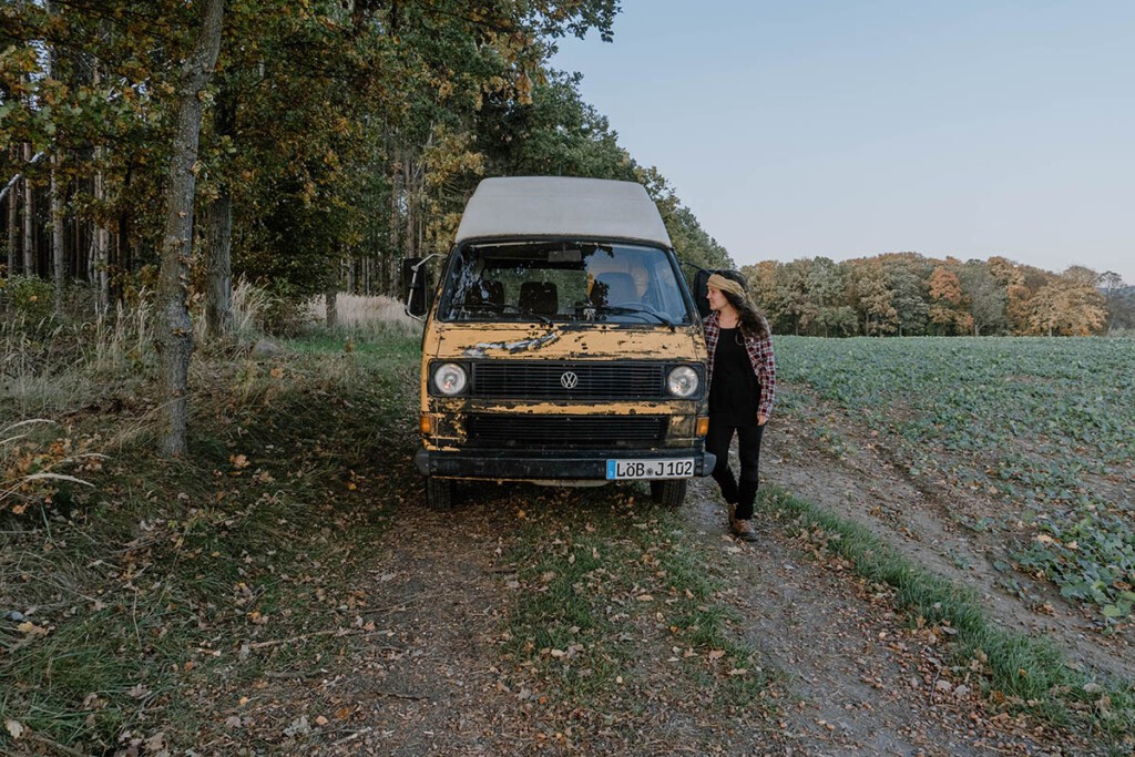 Elisa Model vom Camping Blog take an adVANture steht neben einem alten VW T3 Postbus.