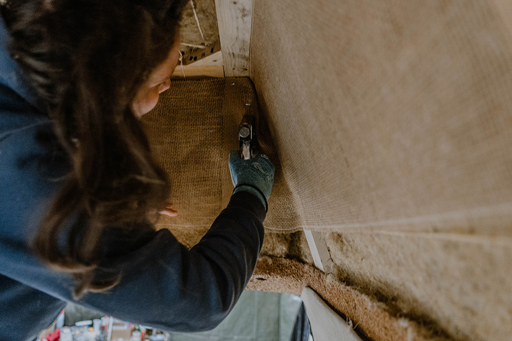 Elisa Model vom Camping Blog take an adVANture befestigt Jutegewebe mit Handtacker in ihrem VW T3 Camper.