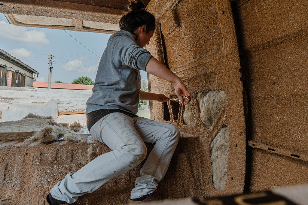 Person nimmt im Wohnmobil Maß, um später Hanfdämmung anzubringen.