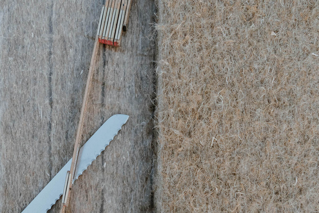 Ein Zollstock und ein Wellenschliffmesser liegen neben einer Hanfdämmmatte.