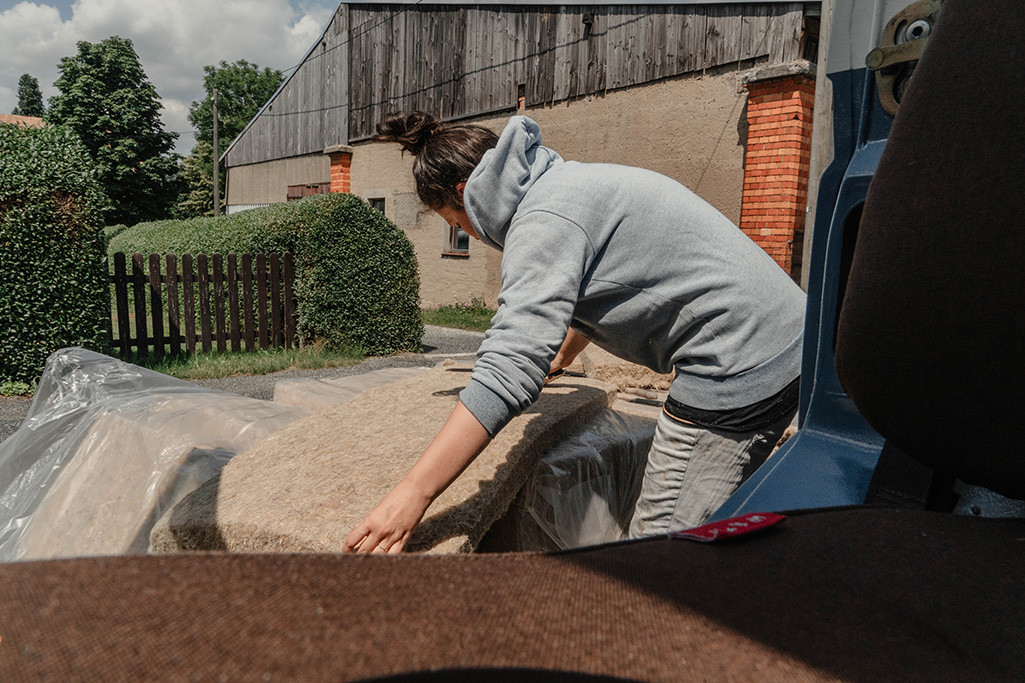 Frau bewegt Hanfdämmmatte, um Maß zu nehmen.