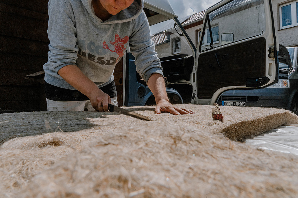 Elisa Model, Baubiologin und Bloggerin vom Camping Blog take an adVANture, schneidet Hanfdämmung fürs Wohnmobil zurecht.