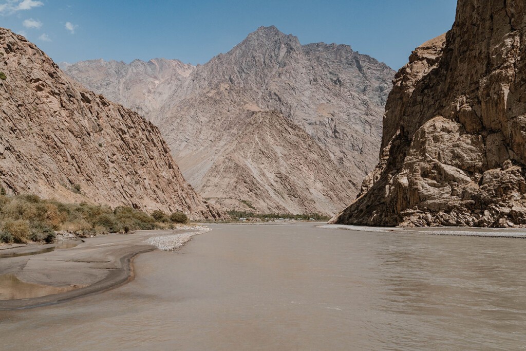 Blick auf den braunen Fluss Bartang, der durchs gleichnamige Tal fließt, umgeben von baumlosen Felswänden.