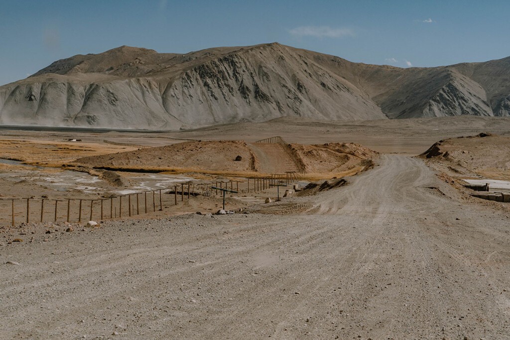 Streckenverlauf der Ferrnstraße M41 entlang der Grenze zu China. Schotterpiste mit Stacheldrahtzaun am Rand.