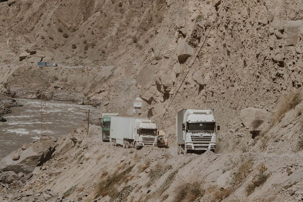 Einige große LKW schlängeln sich auf der schmalen Schotterpiste entlang.