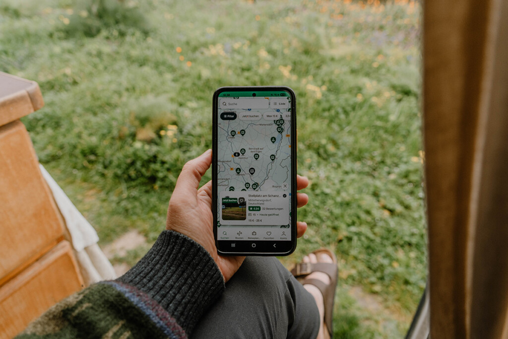 Person hält Smartphone mit geöffneter Campercontact-App in der Hand.