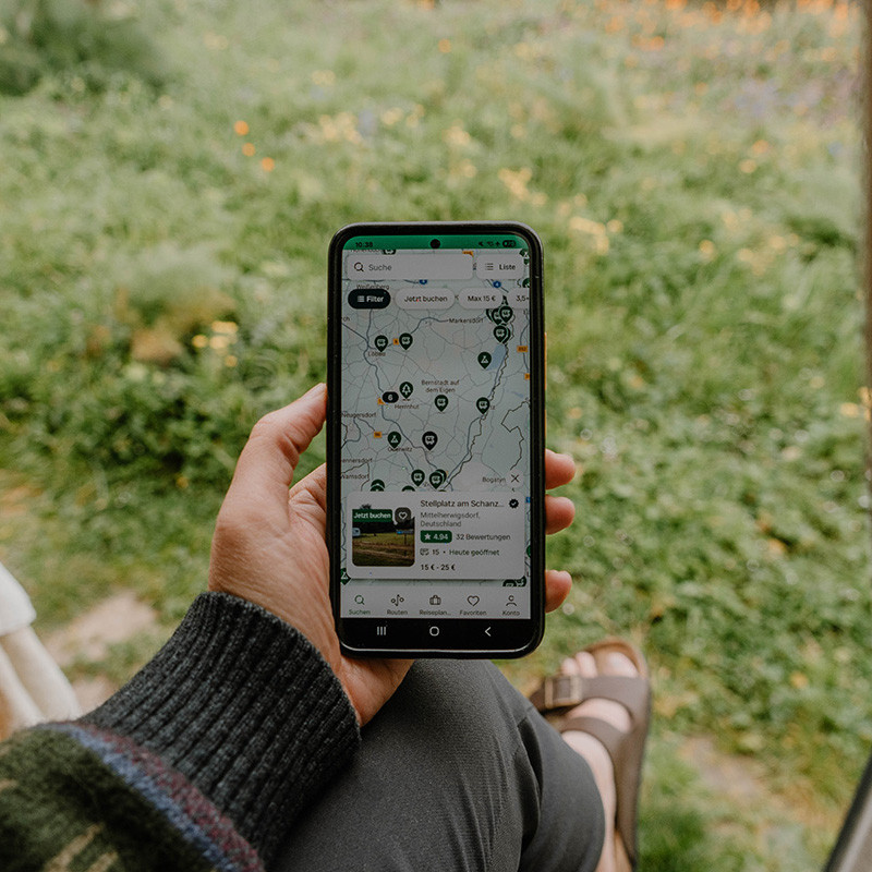 Person hält Smartphone mit geöffneter Campercontact-App in der Hand.