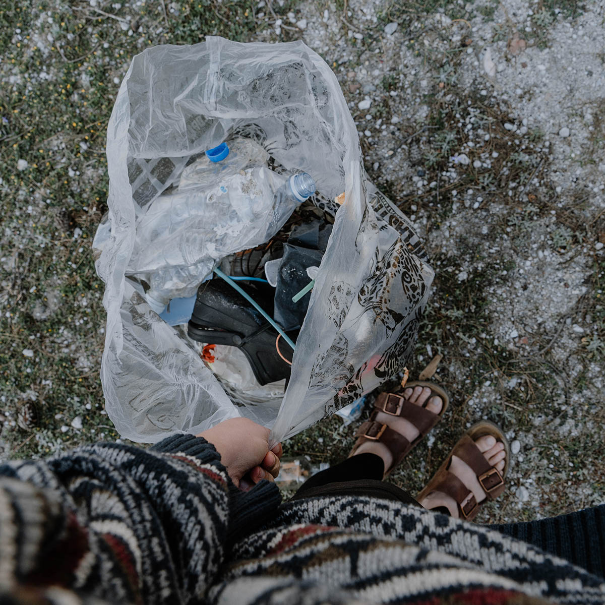 Person hält Müllbeutel in der Hand voller wildem Plastik.